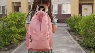 schoolgirl goes school with backpack. view from back. pink school bag on student shoulders