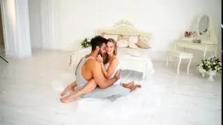 Morning People Loving Each Other in Light Bedroom Next to Bed in Background Table