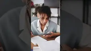 Student Looking at Her Smartphone While Studying