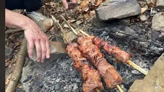 Meat on firewood in mountainous conditions near the river