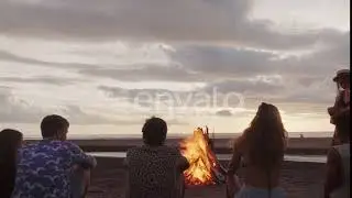 Friends Sitting on Beach in front of Bonfire and Enjoying Evening